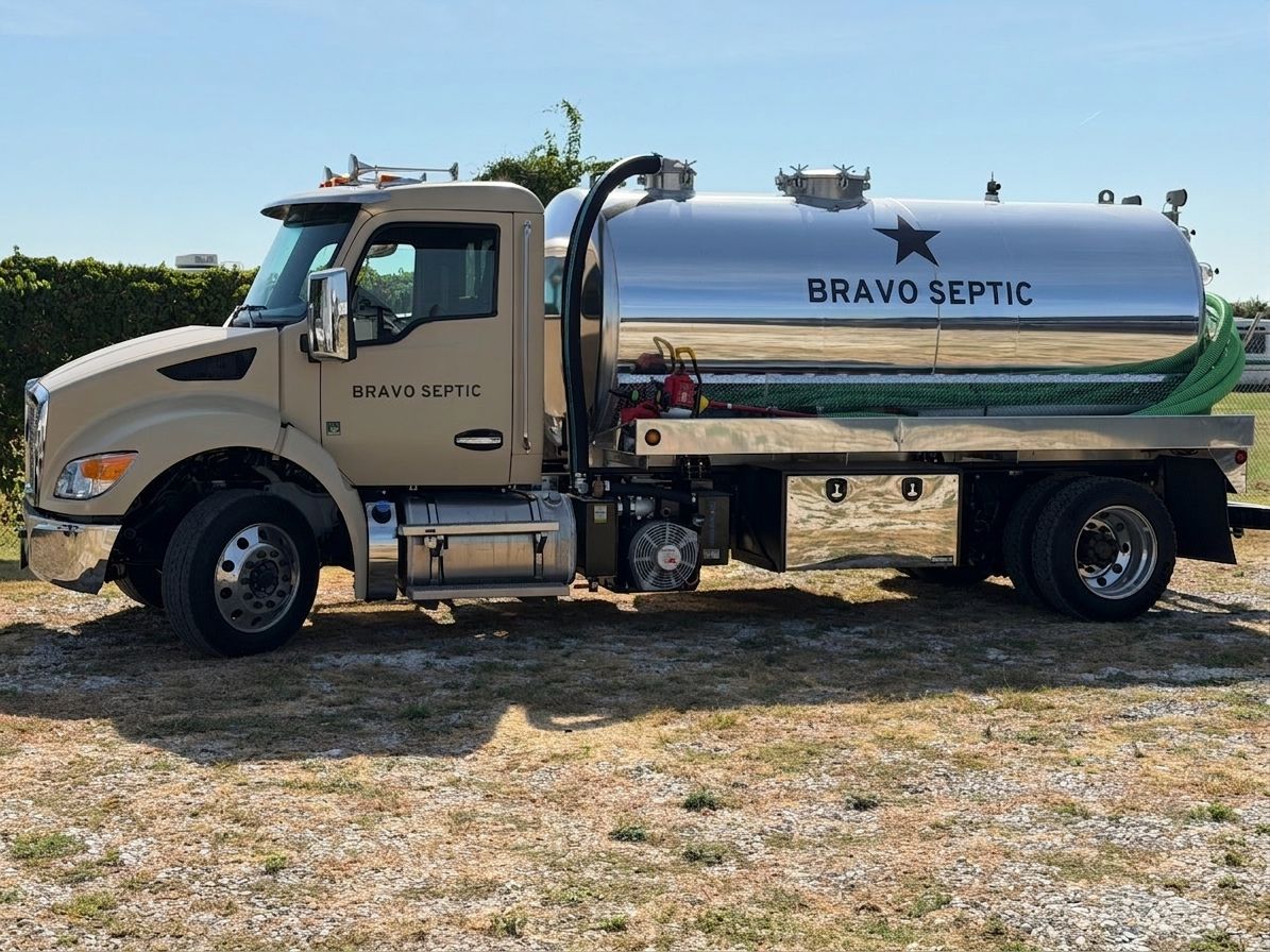A septic service vacuum truck parked in a driveway in front of a Central Texas home.