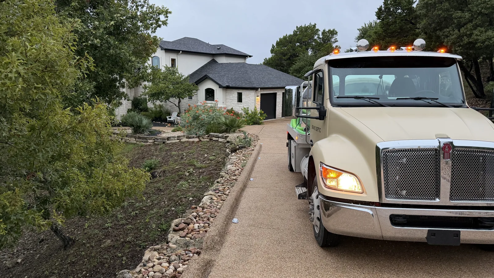 The Bravo Septic pump truck in the driveway of a stone home on a wooded Hill Country lot
