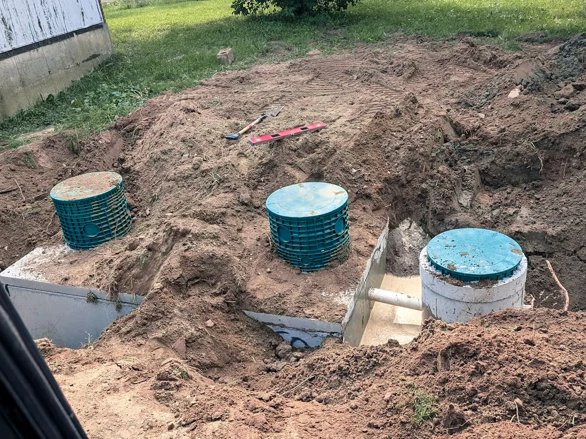 A new concrete septic tank installed in an excavation with its access risers fitted