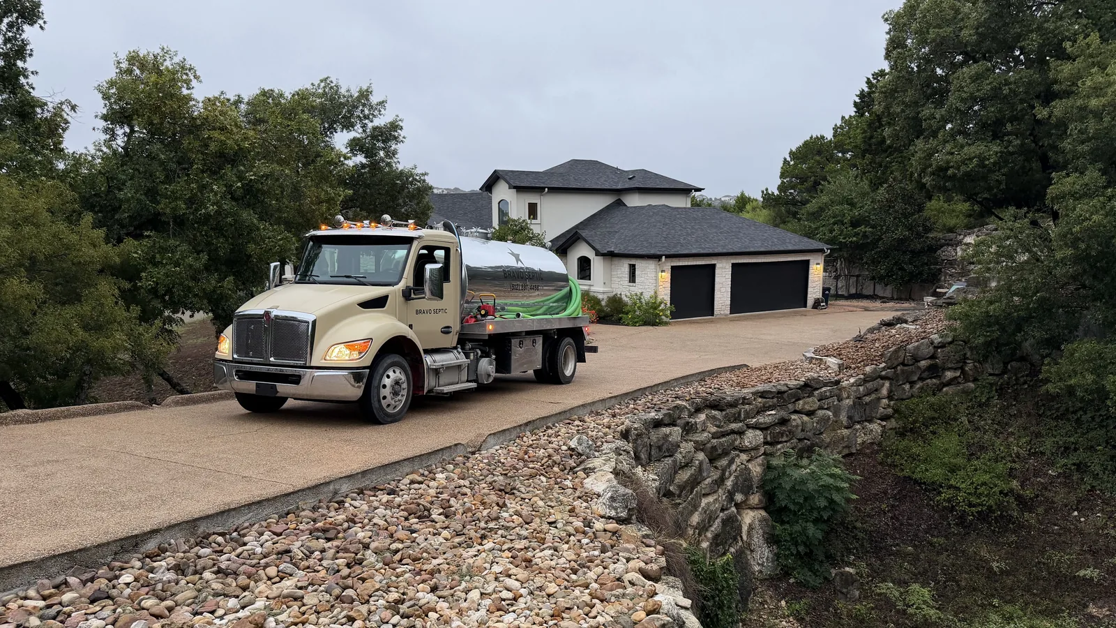 The Bravo Septic pump truck coming down a long driveway to a home on a wooded lot