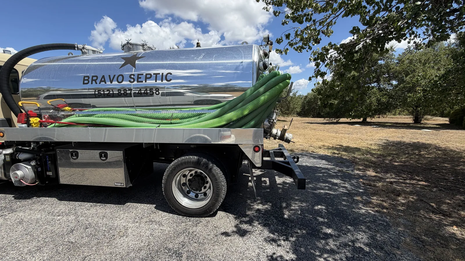 The stainless tank and suction hoses on the Bravo Septic pump truck on a rural lot