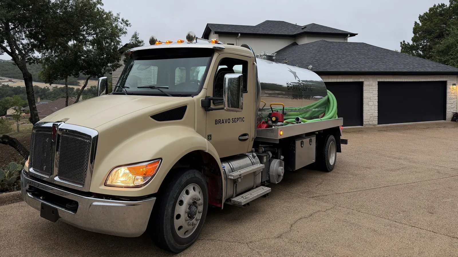 The Bravo Septic pump truck with its lettered stainless tank parked at a Hill Country home