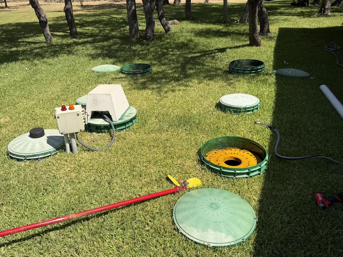 Green septic lids at grade in a yard with access tools laid out